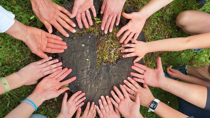 Eine Gruppe von Menschen bildet einen Kreis und legt ihre Hände in die Mitte