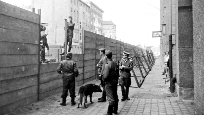 Soldaten mit Hund an Mauer, Stadt im Hintergrund