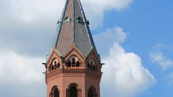 Der Kirchturm hat eine spitze, grüne Kuppel und ist aus rotem Backstein gebaut