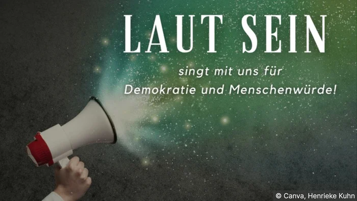 Hand hält Megafon vor Weltraumhintergrund, Text: "Laut sein für Demokratie und Menschenwürde"