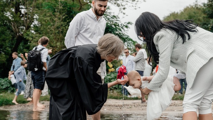 Eine Gruppe von Menschen steht in einem flachen Gewässer und sammelt Müll mit schwarzen Säcken.