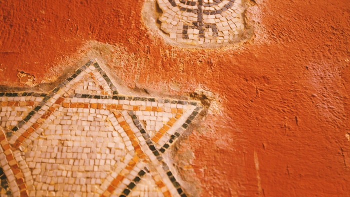 Ein Davidstern und eine Menora sind auf einer roten Wand gemalt