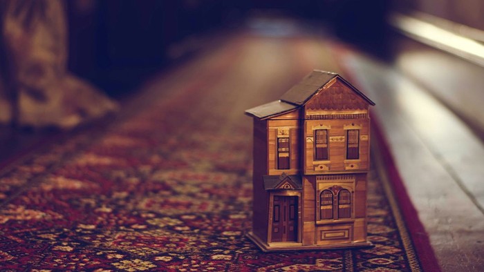 Ein Miniaturhausmodell steht auf einem texturierten Untergrund.