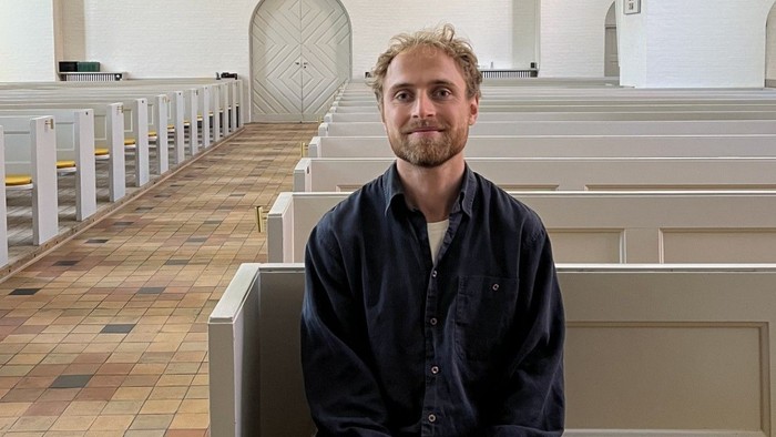 Mand sidder i en kirkebænk i en kirke