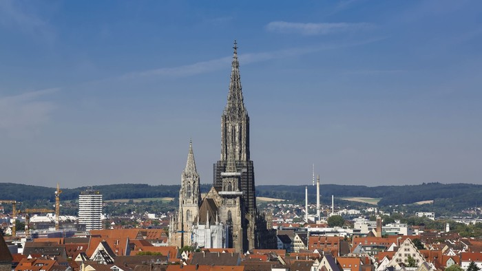 Großstadt mit hohem Kirchturm und vielen roten Dächern