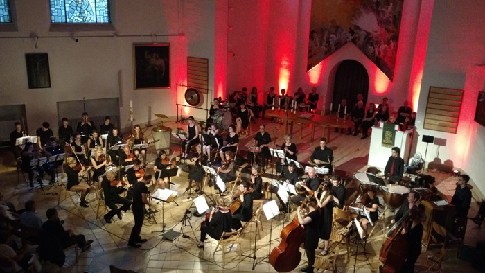 Ein Orchester spielt in einer Kirche vor einem Publikum
