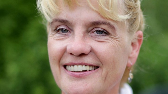 Eine Frau mit blondem Haar lächelt in die Kamera.