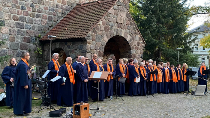 Ein Chor singt vor einem steinernen Gebäude