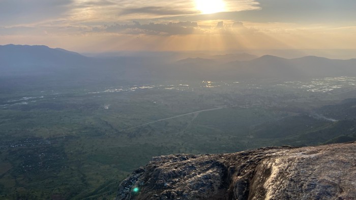 Bergige Landschaft bei Sonnenuntergang mit weitem Blick über Tal und Stadt
