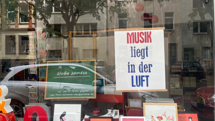 Ein Schaufenster mit Musikinstrumenten und Plakaten, darunter ein großes Schild mit der Aufschrift 