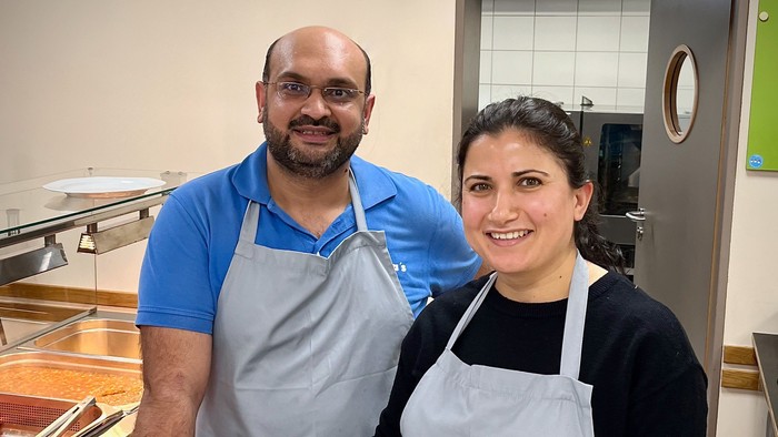 Zwei Menschen in Schürzen stehen in einer Küche