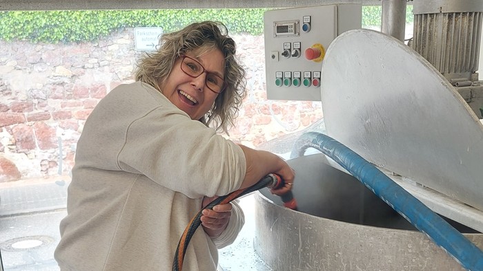 Frau bedient großen Metalltopf in Küche