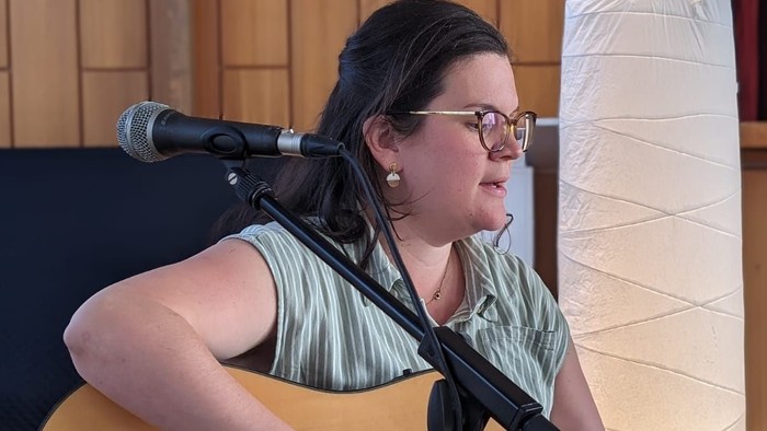 Eine Frau spielt Gitarre und singt in ein Mikrofon