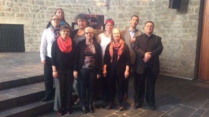 Eine Gruppe von Menschen posiert vor einem steinernen Gebäude