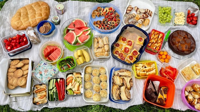 Ein Picknick mit vielen verschiedenen Leckereien auf einer Decke im Gras