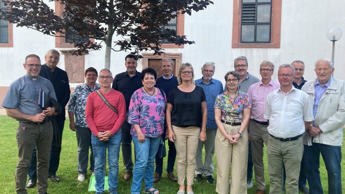 Eine Gruppe von Menschen posiert vor einem Gebäude mit einem Baum