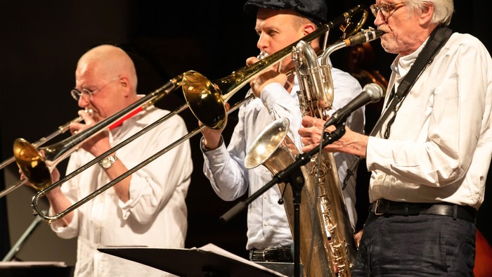 Drei Musiker spielen Blechblasinstrumente auf Bühne
