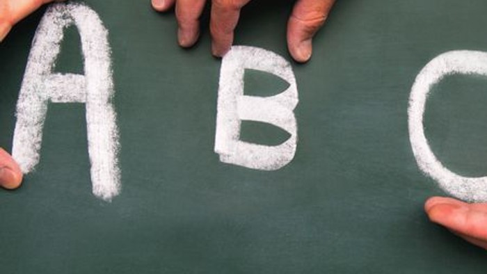 Hände schreiben ABC auf Tafel