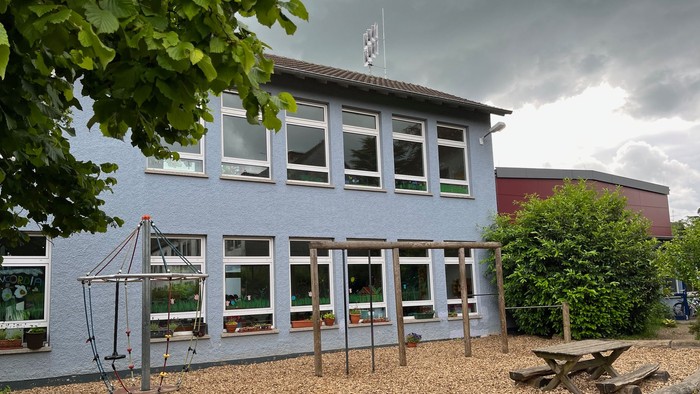 Haus mit blauer Fassade und Außenbereich mit Sitzbänken und Spielgeräten