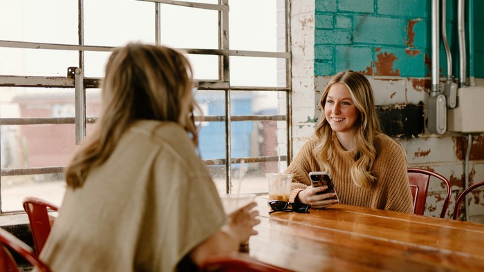 Zwei Frauen sitzen an einem Tisch und unterhalten sich.