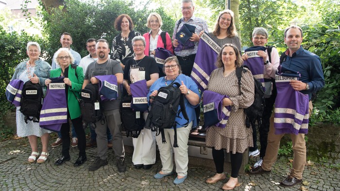 Eine Gruppe von Menschen hält Taschen mit dem Aufdruck
