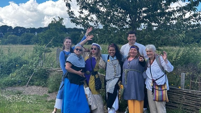 Eine Gruppe von Menschen posiert in historischen Kostümen vor einem Baum
