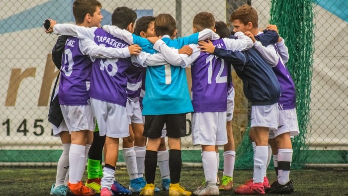 Eine Gruppe von jungen Fußballern steht beisammen und hat die Arme umeinander gelegt.