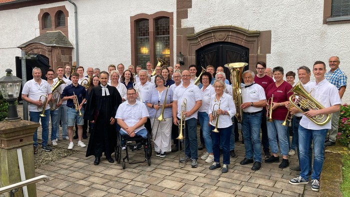 Gruppe von Personen, die mit Musikinstrumenten vor einem Gebäude posieren