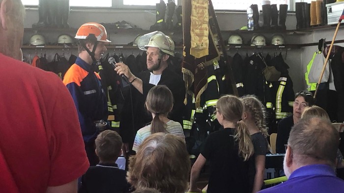 Feuerwehrleute zeigen Kindern ihre Ausrüstung in einer Werkstatt