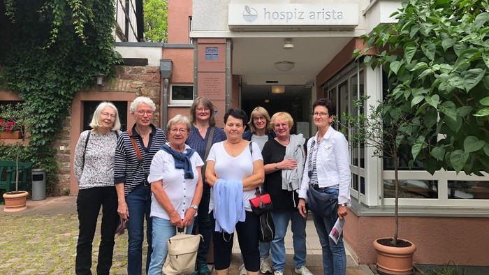 Eine Gruppe von Menschen steht vor einem Gebäude mit der Aufschrift "Hospiz Arista".