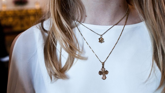 En kvinde med guldhalsbånd og kors med hår i baggrunden