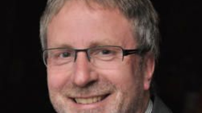 Mann mittleren Alters mit Brille, lächelnd.