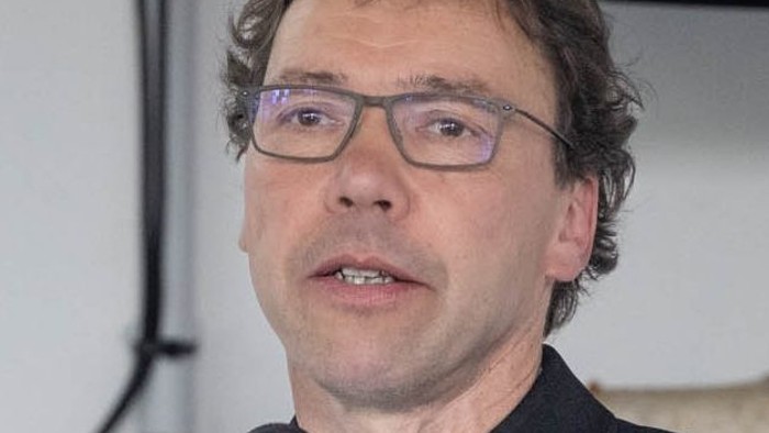 Ein Mann in schwarzer Robe spricht in ein Mikrofon.