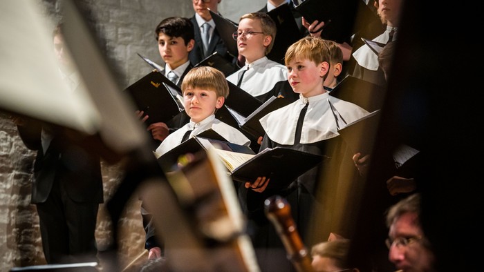 Junge Sänger in weißen Chorhemden singen in einem Kirchenchor