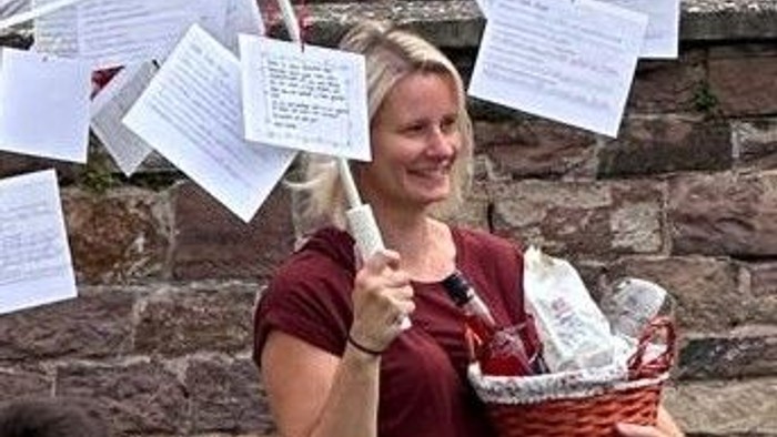 Frau hält Regenschirm mit Zetteln, während Kinder um sie herumstehen.