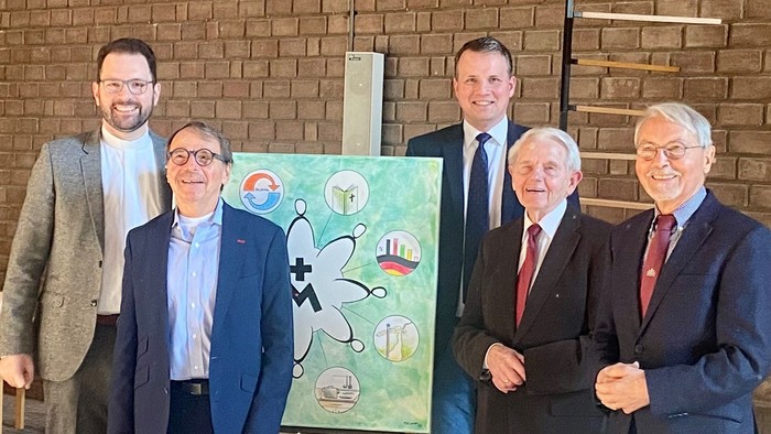 Fünf Männer posieren vor einem Bild mit Cartoonfigur