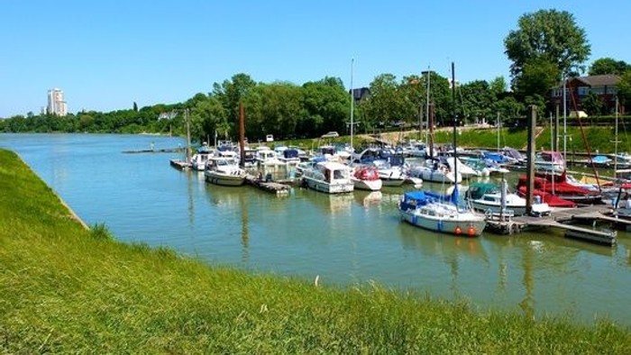 Ein Hafen mit mehreren Booten, umgeben von grünem Gras und Bäumen unter klarem Himmel