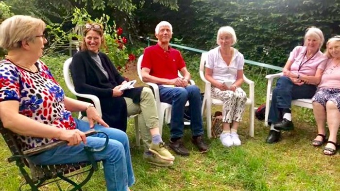 Gruppe von Menschen, die draußen auf Stühlen sitzt