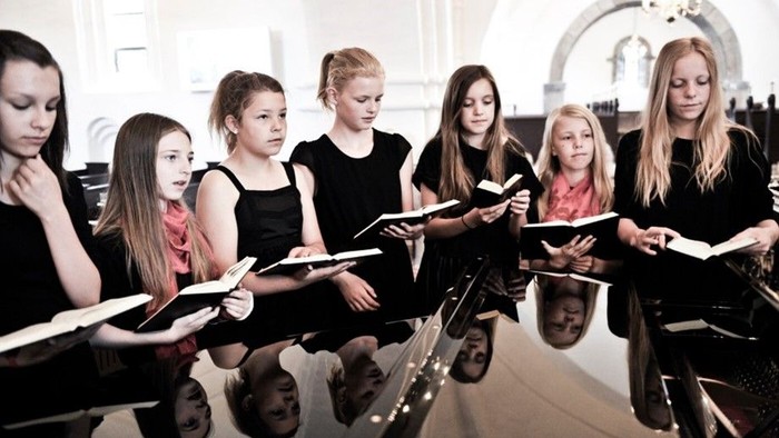 En gruppe unge piger synger i en kirke.