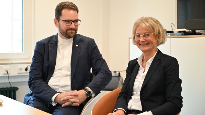 Zwei Personen sitzen in einem Büro und unterhalten sich.
