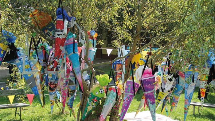 Bunte Drachen im Garten, einige auf Stangen, andere auf dem Boden