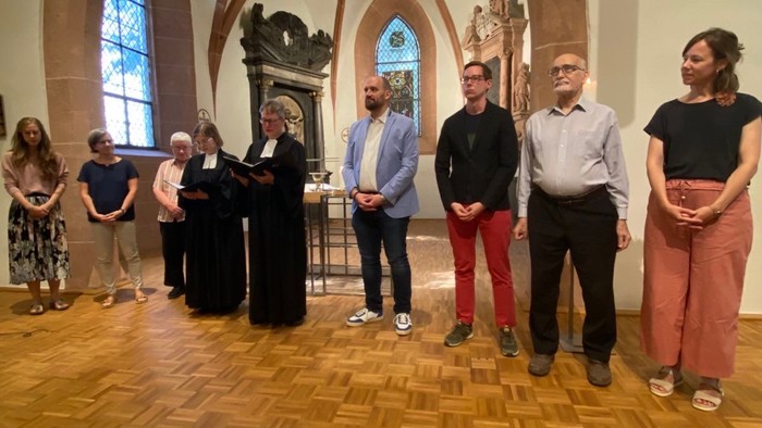 Eine Gruppe von Menschen steht in einer Kirche und unterhält sich.