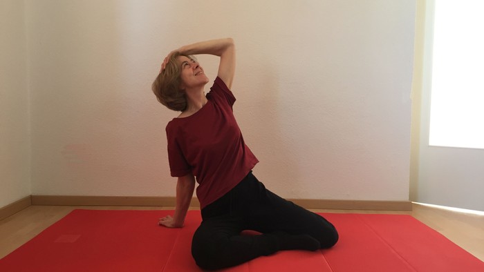 Ein Mädchen sitzt auf einer Yogamatte und streckt sich.