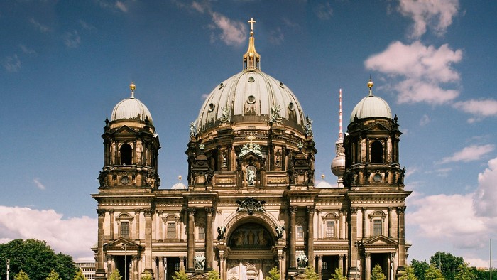 Großartige Kathedrale mit zwei Kuppeltürmen und zentralem Hauptdom, umgeben von Grünflächen und Menschen