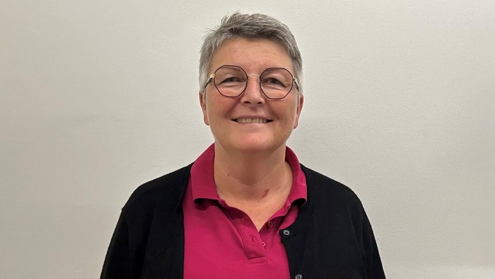 En kvinde med kort hår og briller, smilende.