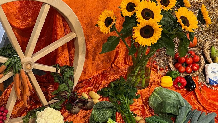 Bunter Herbsttisch mit Sonnenblumen, Gemüse und Holzrad