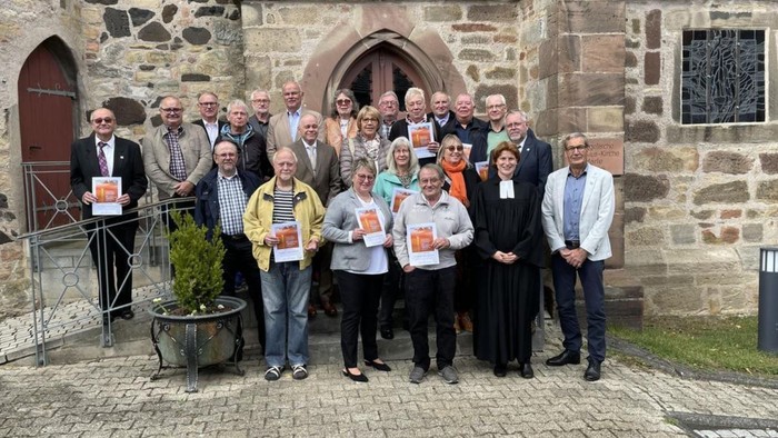 Gruppe von Personen, die vor einem alten Steingebäude posieren.