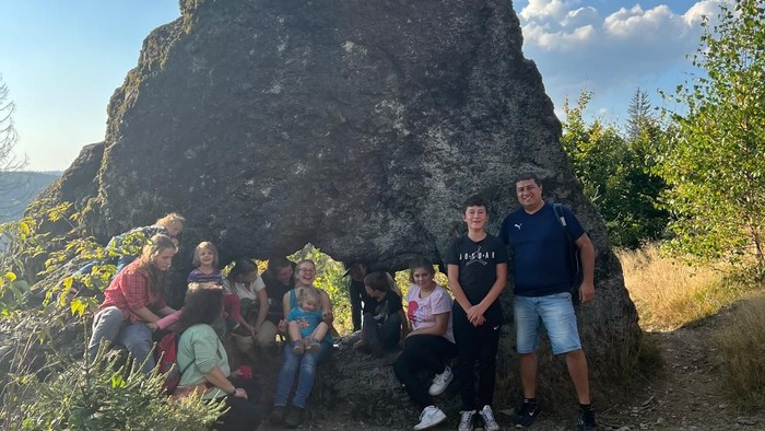 Familie posiert vor großer Felsformation in der Natur