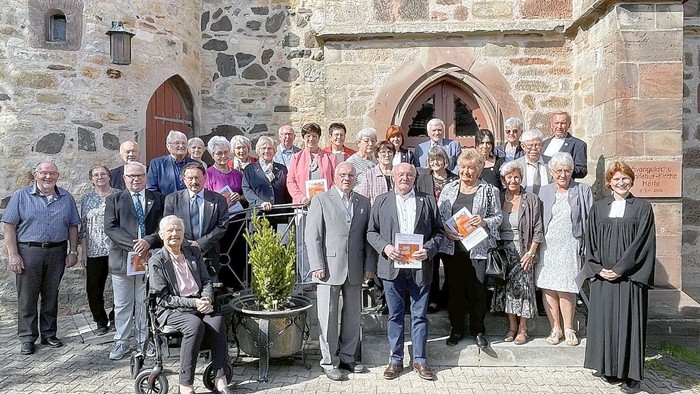 Gruppe von Personen, die vor einem alten Steingebäude posieren.