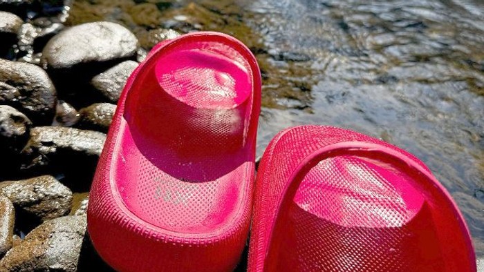Rosa Badeschlappen auf Felsen in der Nähe von Wasser.